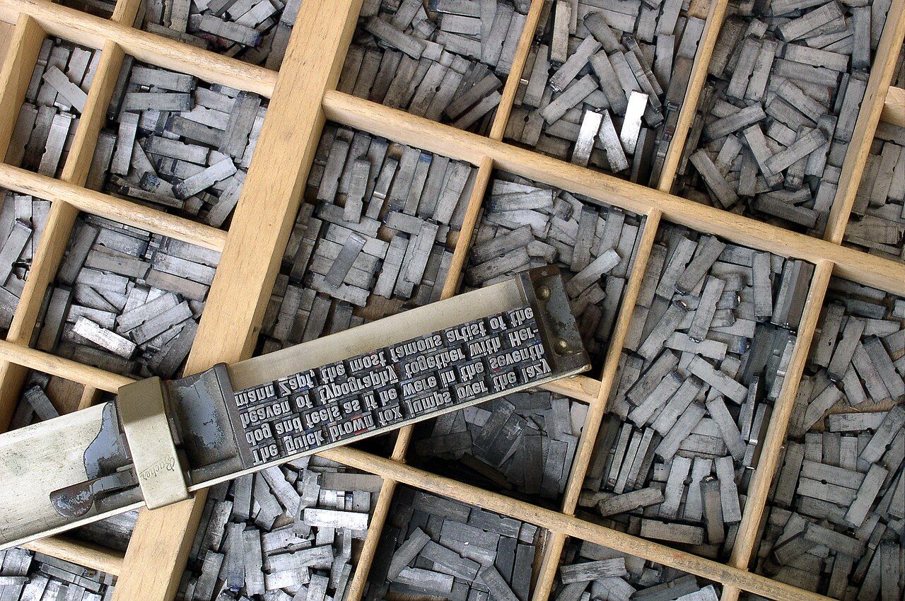 Metal movable type arranged in a composing stick, showing words assembled one character at a time