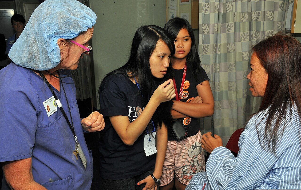 Language access is a clinical intervention rather than a courtesy &mdash; the trained interpreter sits beside the encounter while the nurse speaks to the patient, not about her.