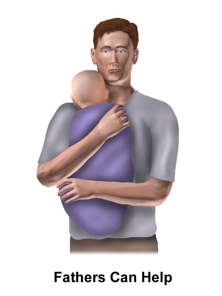 Caregiver seated at eye level holding the hand of an older adult and speaking calmly in a bright quiet room