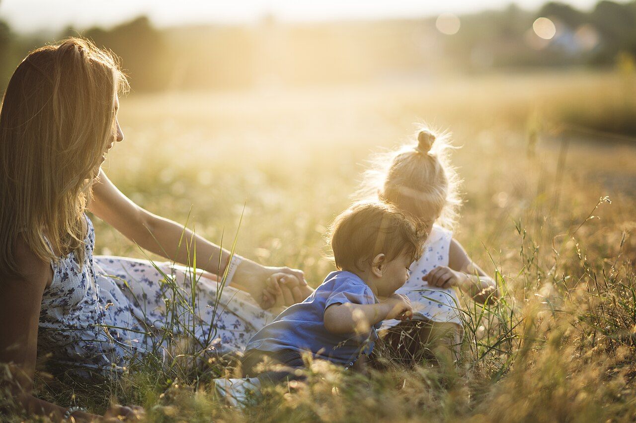 A parent and two young children exploring nature outdoors